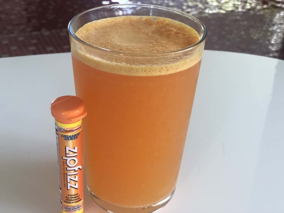 A tube of Zipfizz beside a glass of the energy drink mix