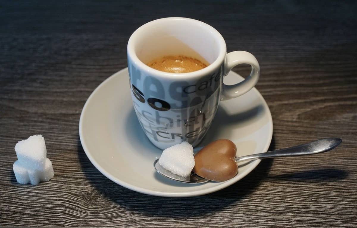 A cup of coffee with a few sugar blocks.