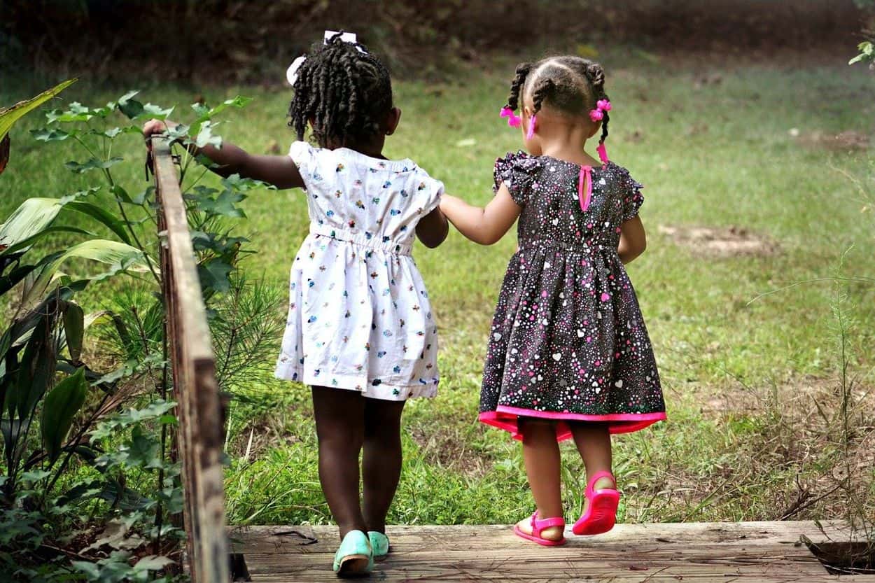 Two baby girls walking hand in hand.
