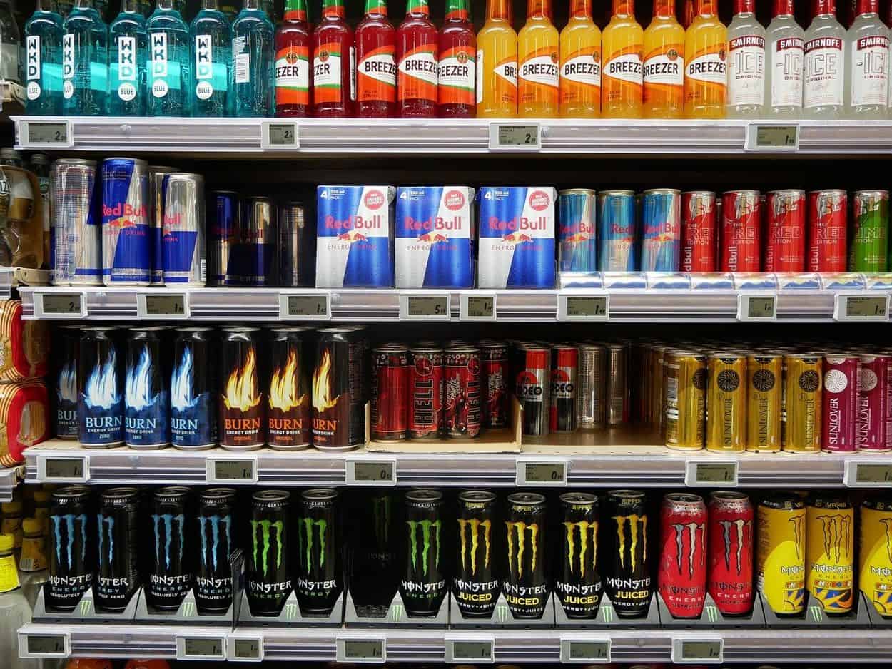 Canned energy drinks are arranged on a shelf for the purpose of selling.
