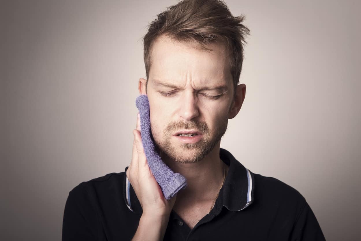 person holding his face due to tooth pain