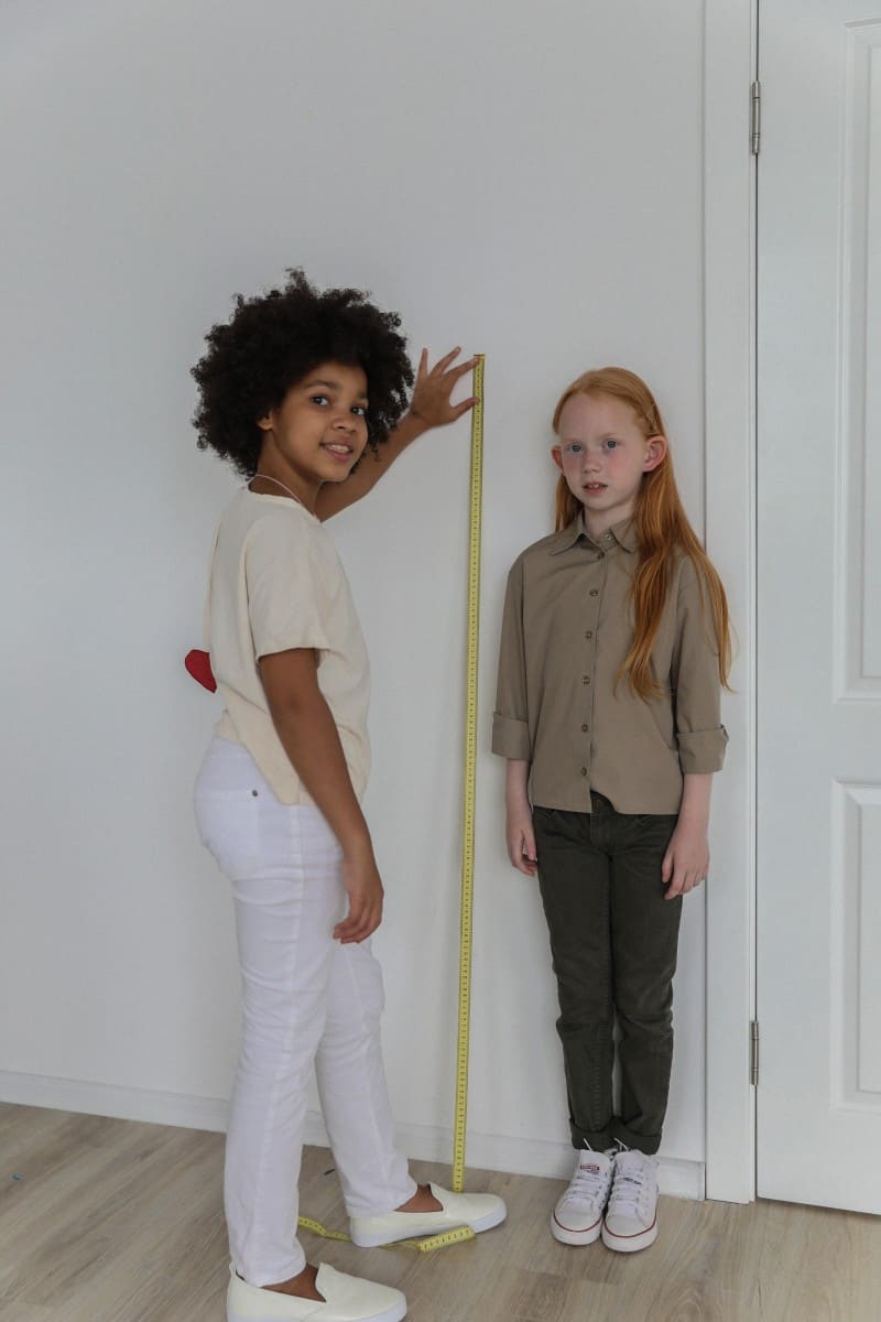 two little girls measuring height.